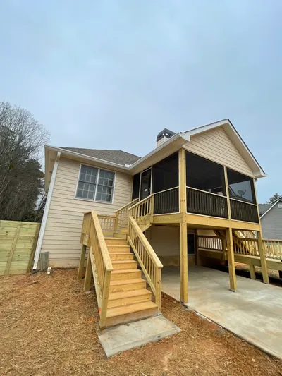 Completed elevated wood deck with screened upper porch and wooden stairs at a single-story home