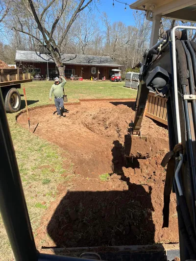 Excavation and grading in progress in a residential backyard with machinery and crew
